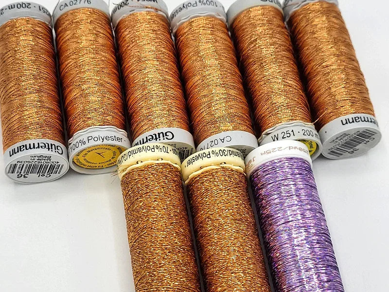 Set of metallic thread spools on a white background