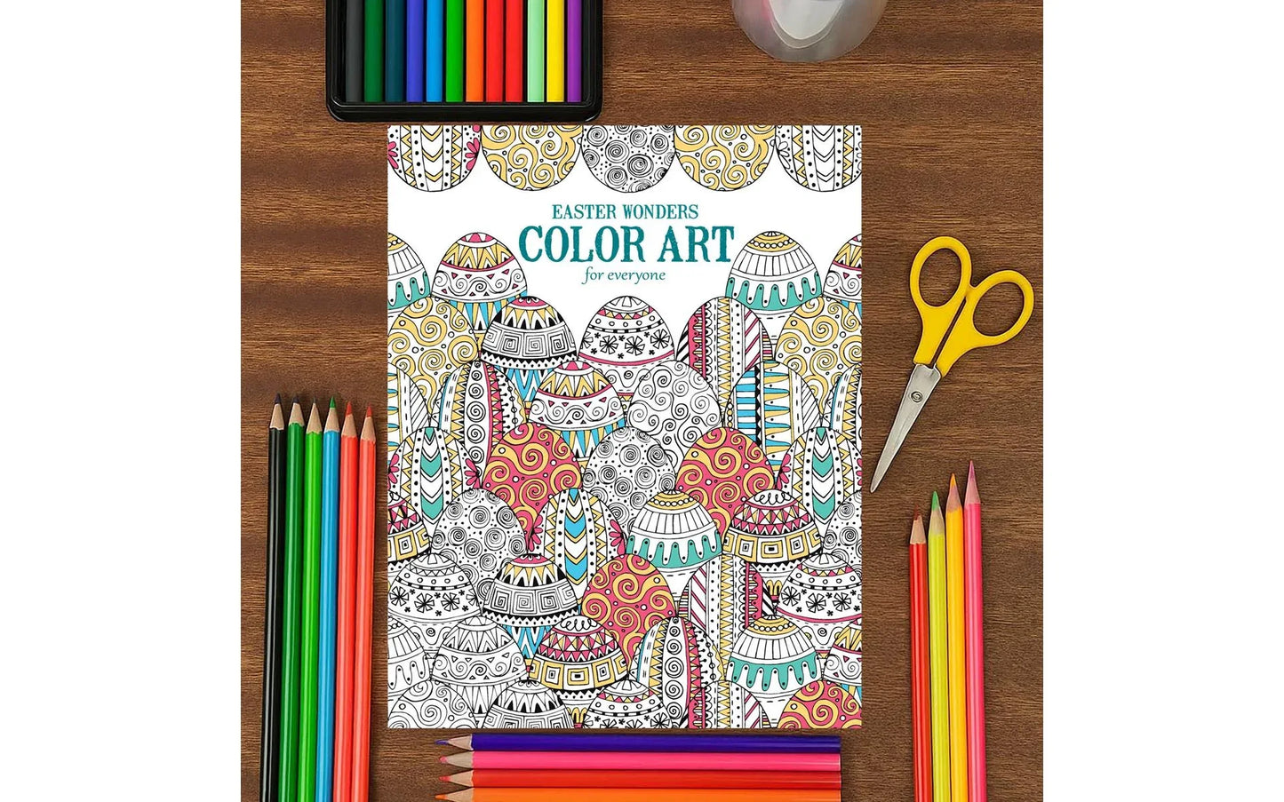 Coloring book with Easter designs on a wooden table with art supplies.