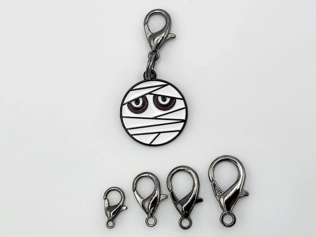 Mummy stitch markers with lobster clasp attachments — flat lay sampler of clasp sizes