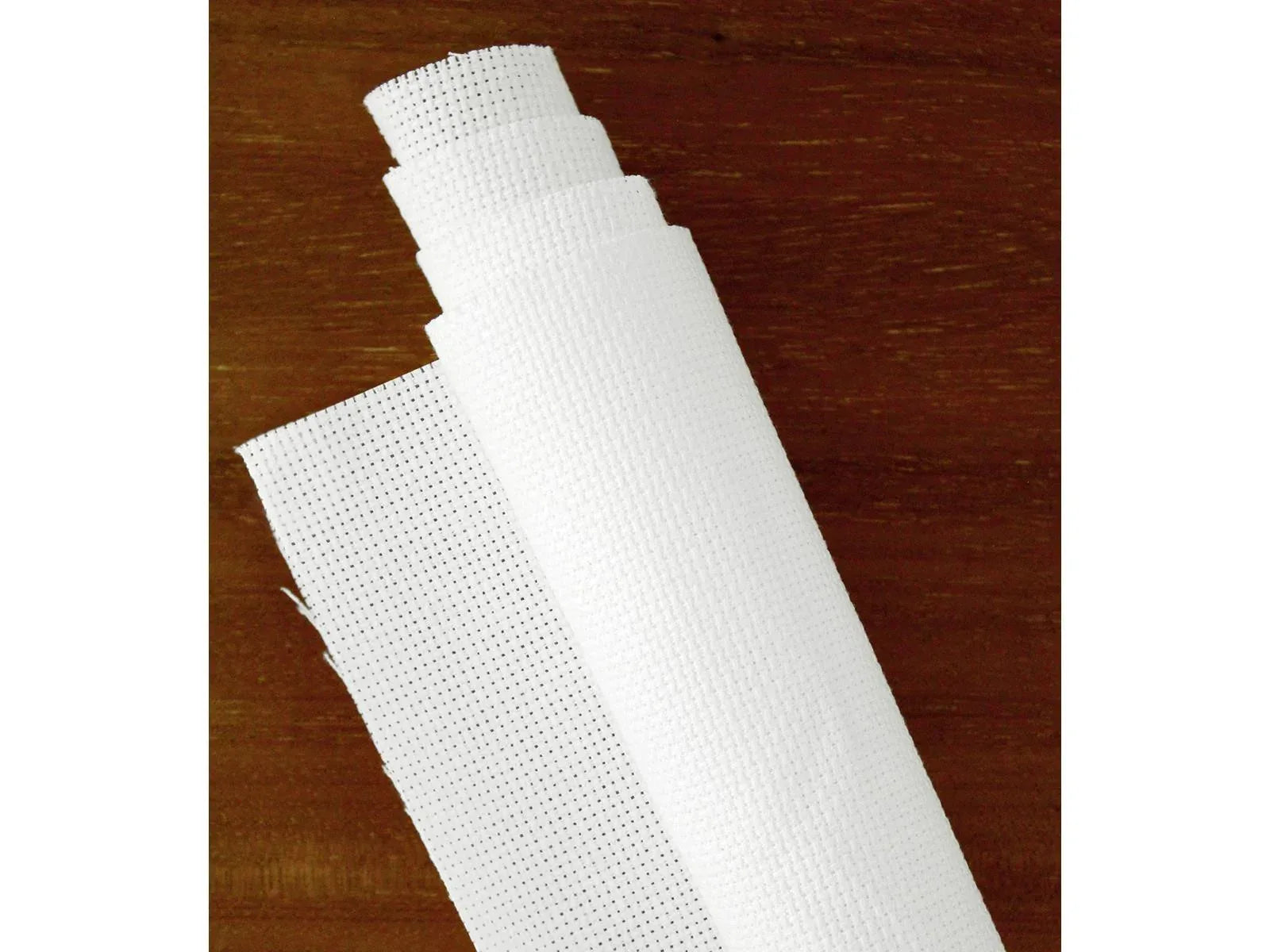 Roll of white mesh fabric on a wooden surface