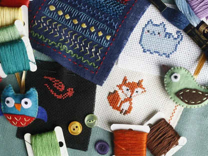 Cross-stitched fabric with animal designs and embroidery threads.
