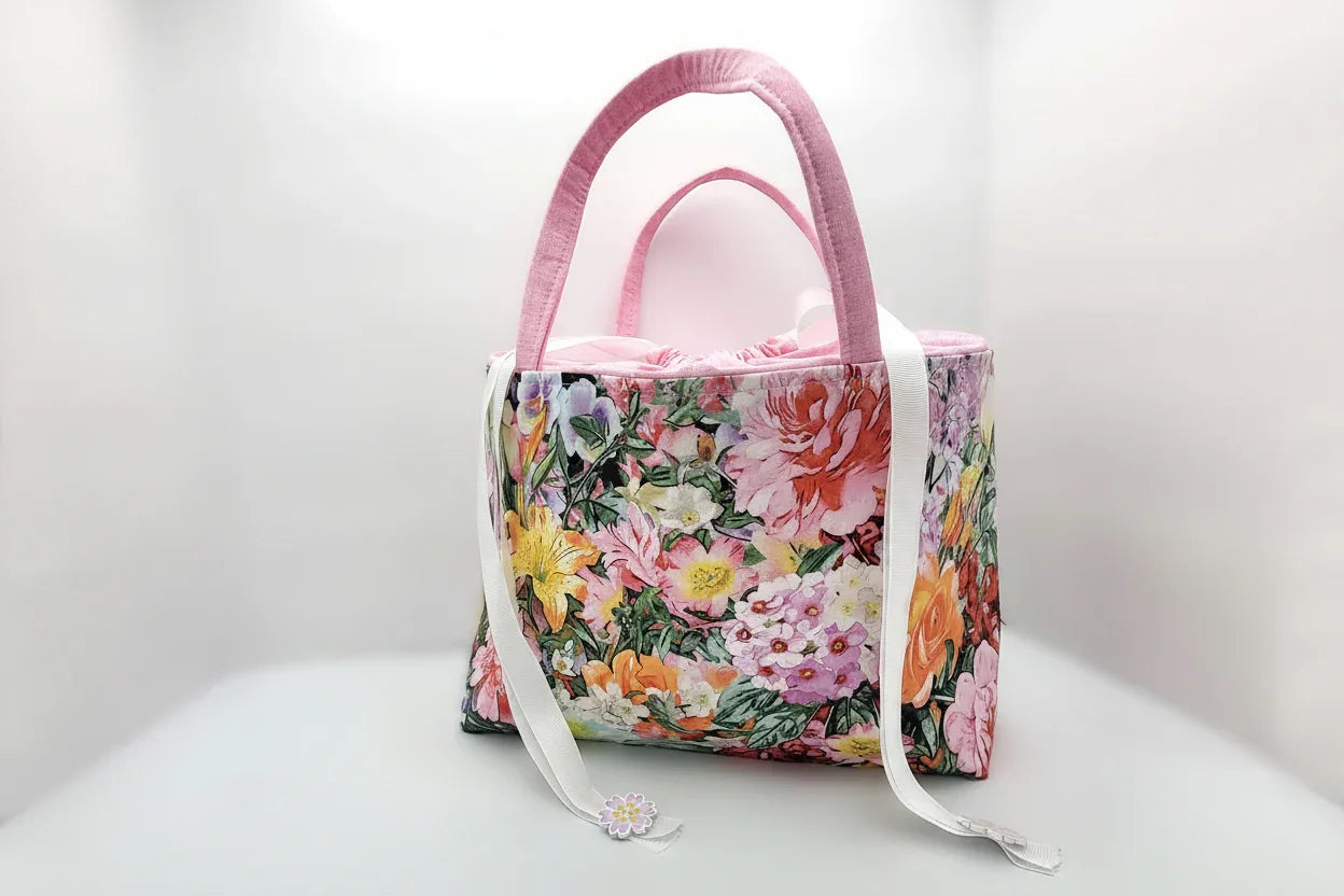 Floral-patterned handbag with pink handle on a white background
