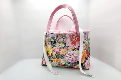 Floral-patterned handbag with pink handle on a white background