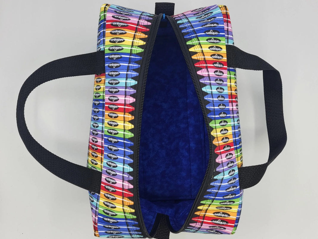 Interior view of crayon print duffle bag showing open zipper and spacious main compartment