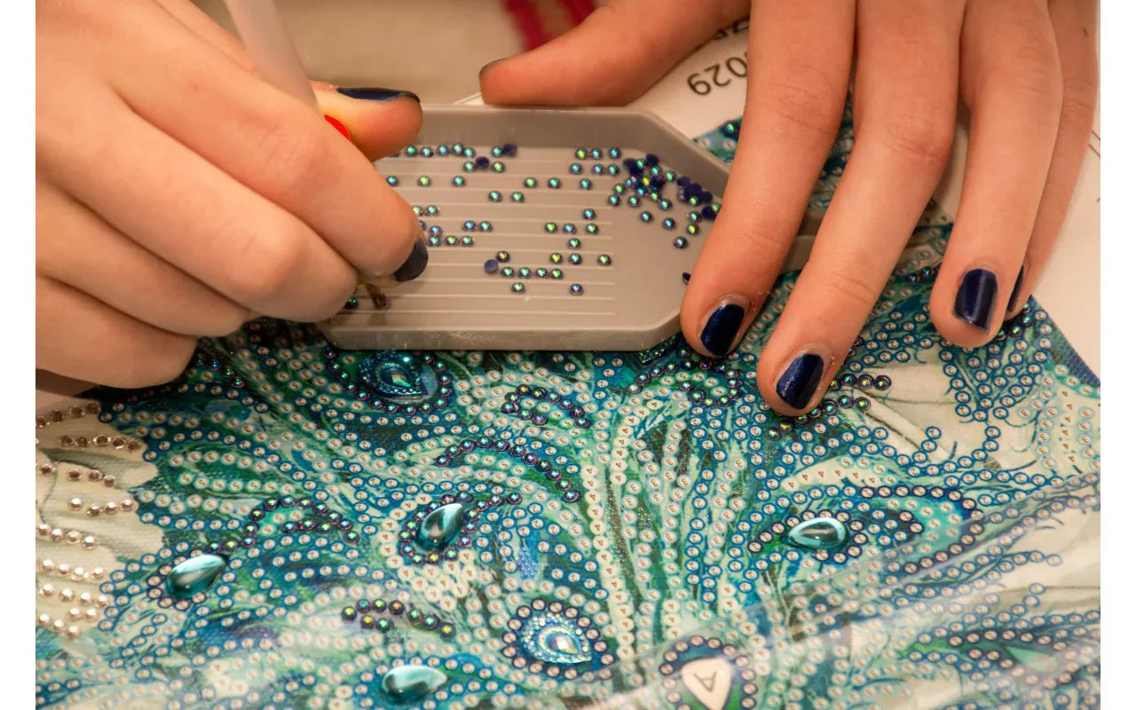 Person applying rhinestones to a decorative surface