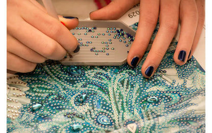 Person applying rhinestones to a decorative surface