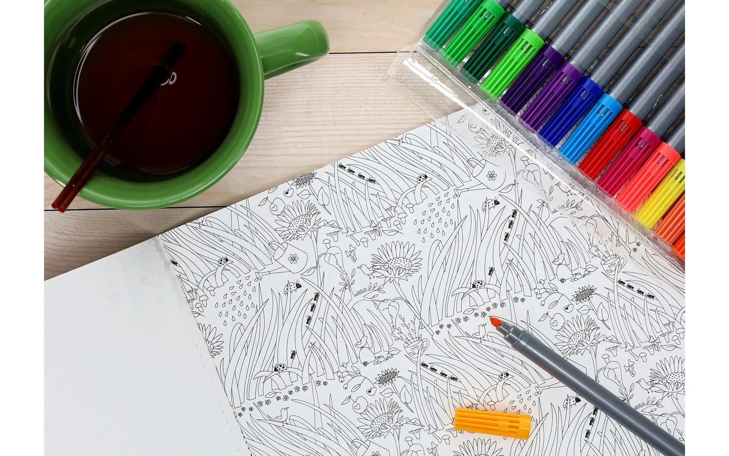 Coloring book with a cup of tea and coloring pencils on a wooden table