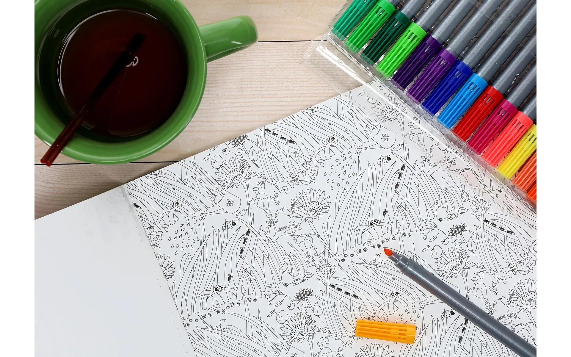 Coloring book with a cup of tea and coloring pencils on a wooden table