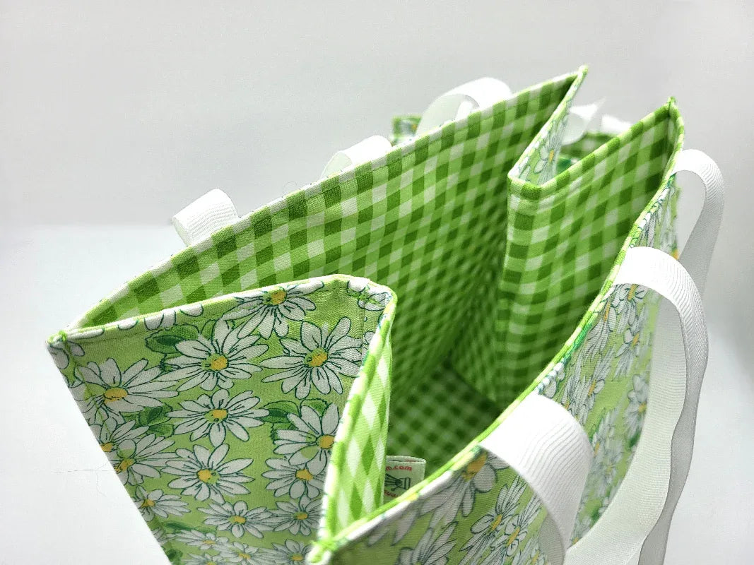 Green checkered and floral fabric bag with white handles on a light gray background