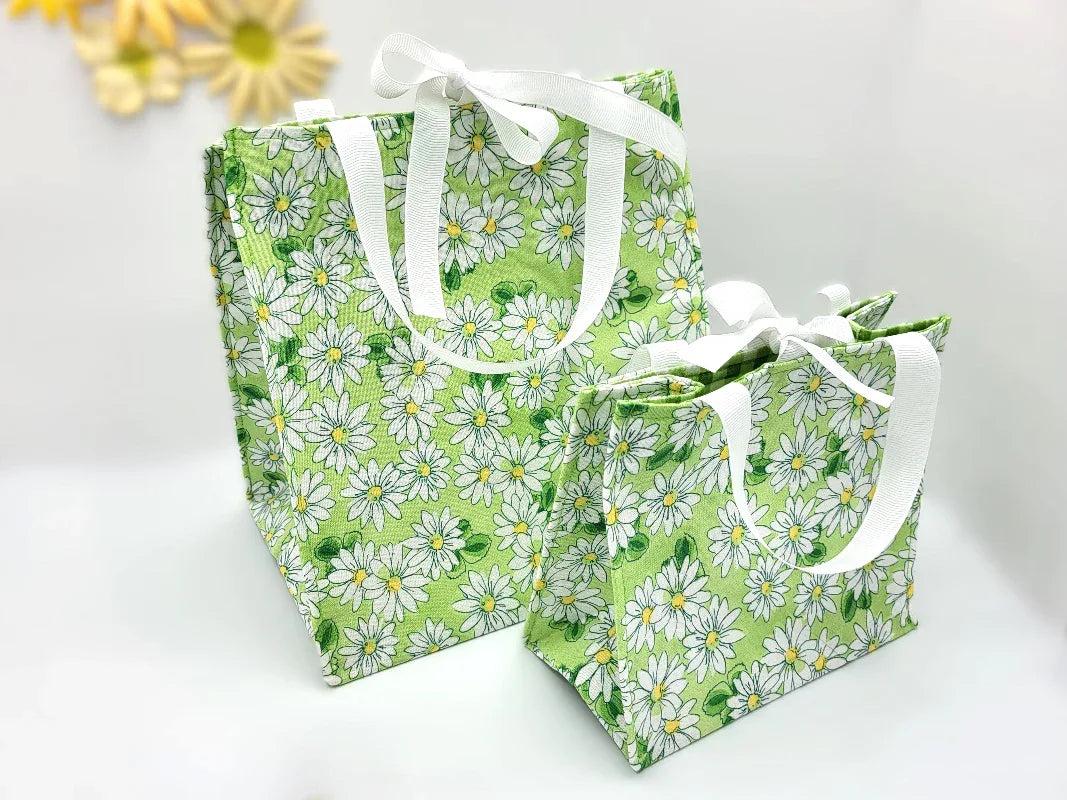 Two green floral-patterned bags with white handles on a light background