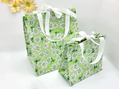 Two green floral-patterned bags with white handles on a light background