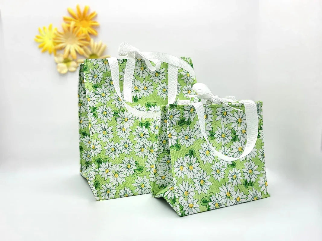 Two green tote bags with white floral patterns on a white background