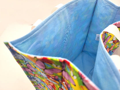 Colorful butterfly-patterned fabric inside a blue bag with a visible brand tag.