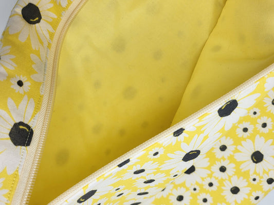 Close-up of a yellow fabric with white floral patterns and black centers.