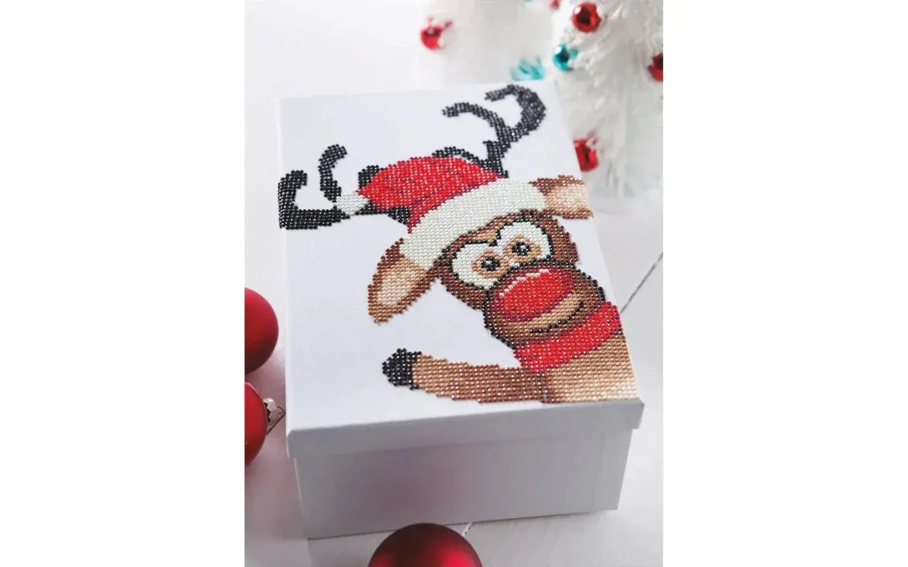 Cross-stitched design of a reindeer on a white box with Christmas decorations.