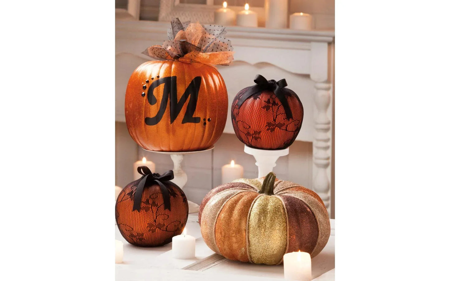 Decorative pumpkins with a 'M' on a white surface with candles
