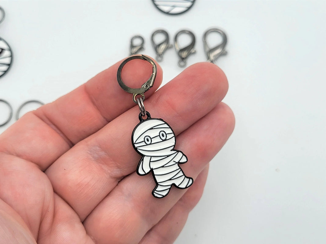 Mummy stitch marker with round clasp attachment, handheld close-up
